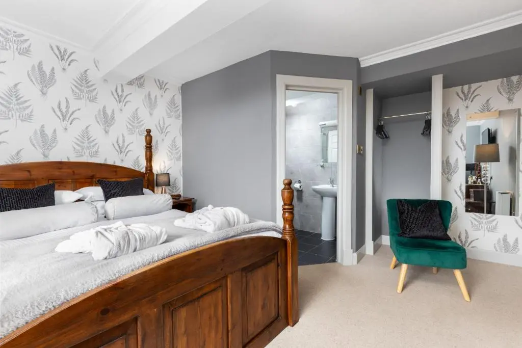 a bedroom with a wooden bed and a green chair at Dornoch Castle Hotel in Dornoch