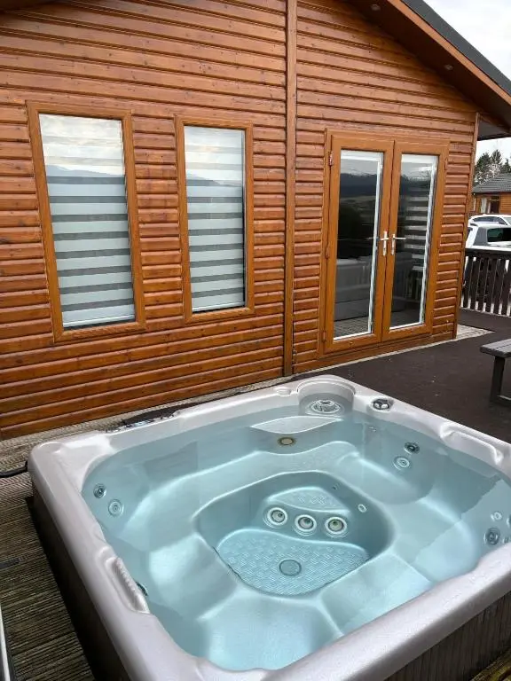 a jacuzzi tub in front of a house at Clochnaben lodge in Strachan