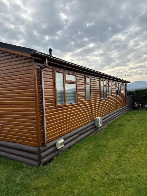 a wooden cabin with windows on a grass field at Clochnaben lodge in Strachan