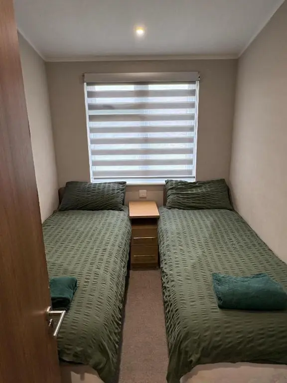 a small room with two beds and a window at Clochnaben lodge in Strachan