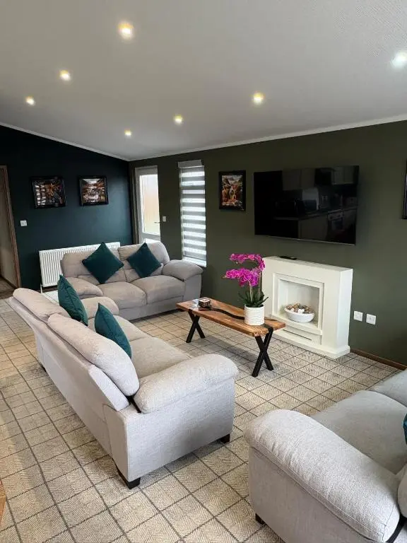 a large living room with couches and a tv at Clochnaben lodge in Strachan