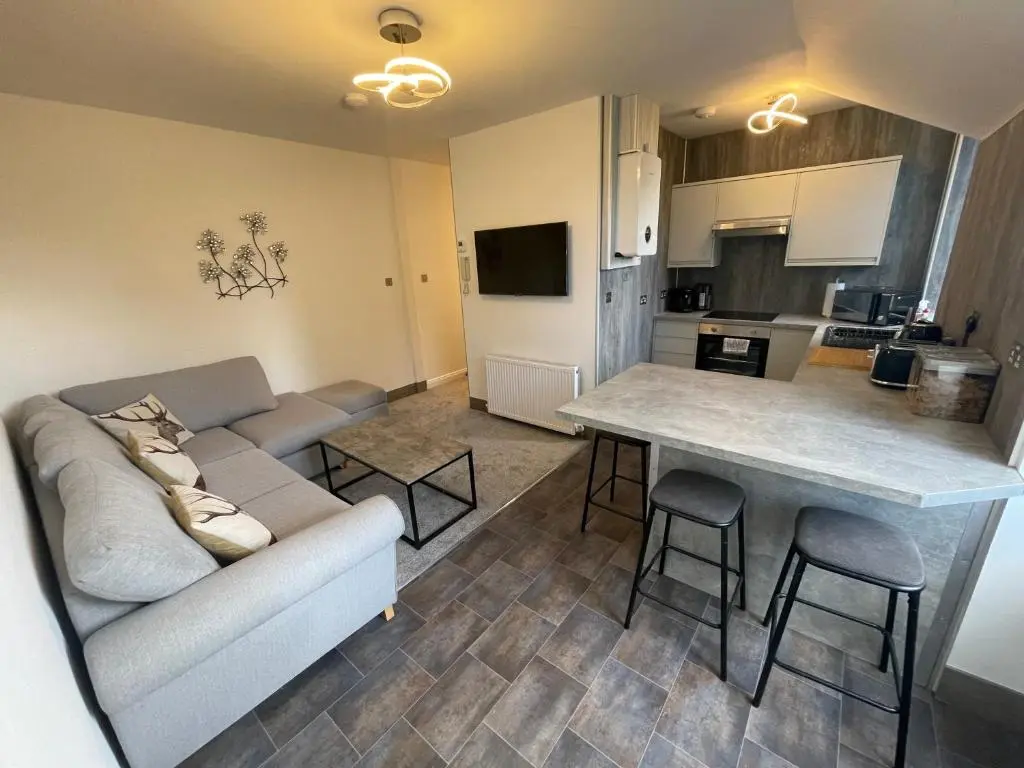 a living room with a couch and a table at Crown \u00e0ros beag, Ultra City Central 2 bedroom apartment with free parking onsite in Inverness