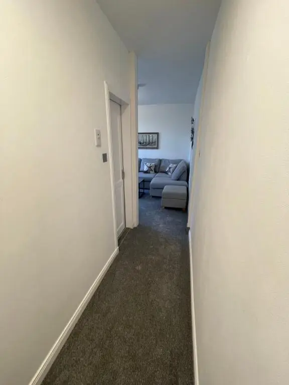 a hallway with a living room and a couch at Crown \u00e0ros beag, Ultra City Central 2 bedroom apartment with free parking onsite in Inverness