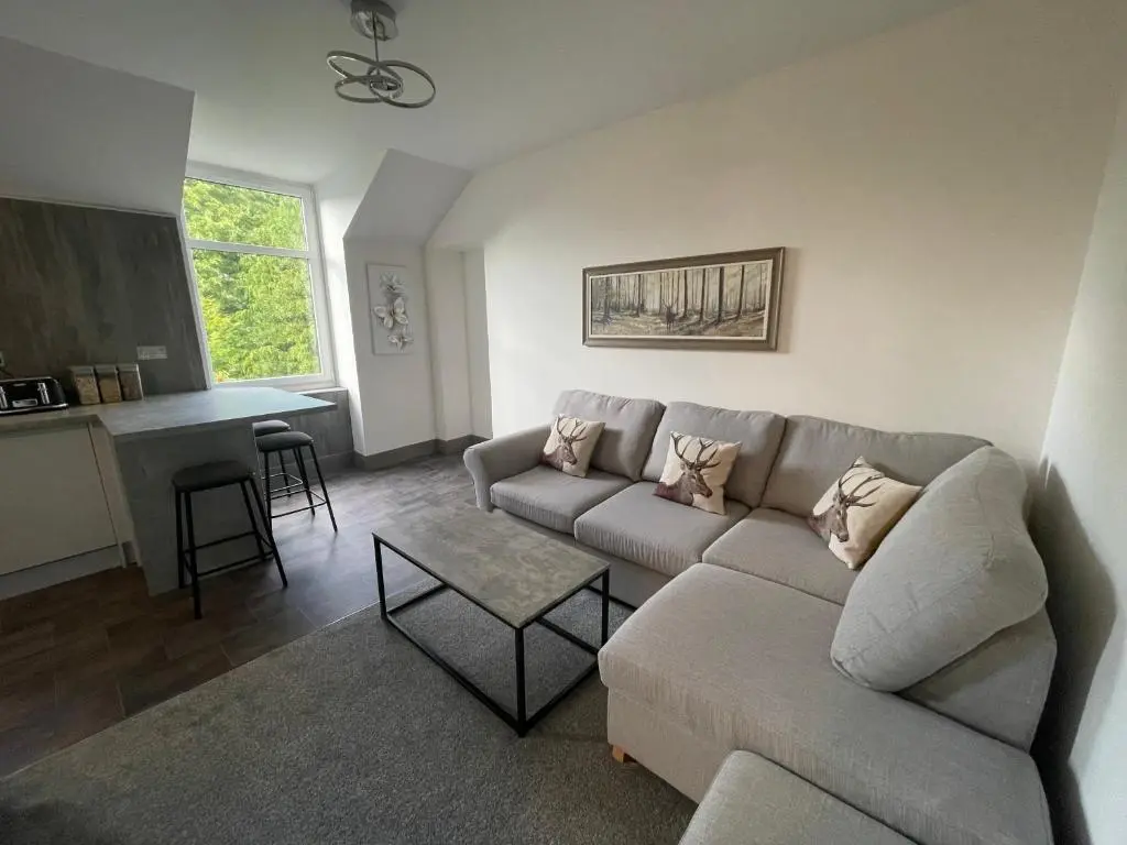 a living room with a couch and a table at Crown \u00e0ros beag, Ultra City Central 2 bedroom apartment with free parking onsite in Inverness