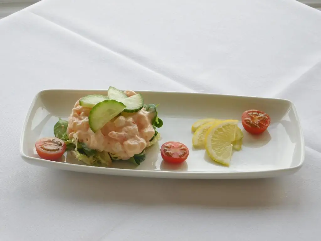 a plate of food with shrimp and tomatoes and lime slices at Cullen Bay Hotel in Cullen