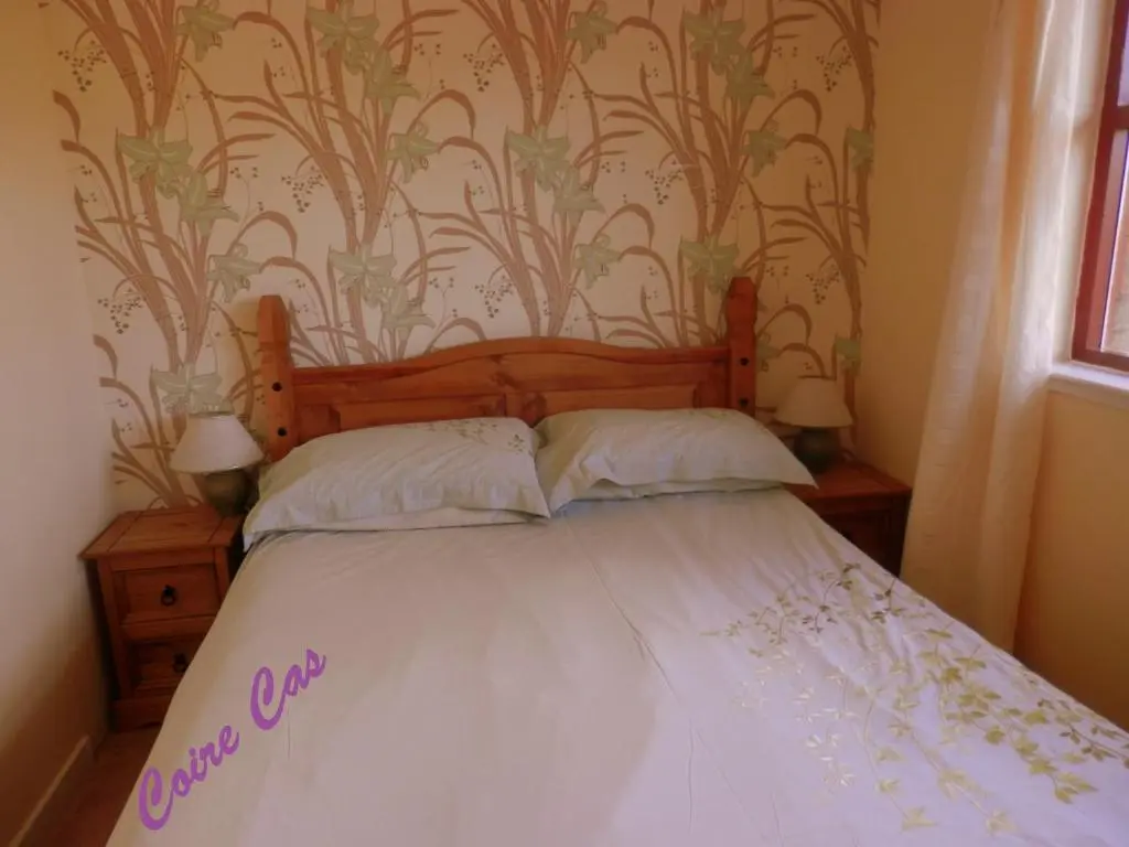 a bedroom with a bed with white sheets and wallpaper at Cairngorm Highland Bungalows in Aviemore