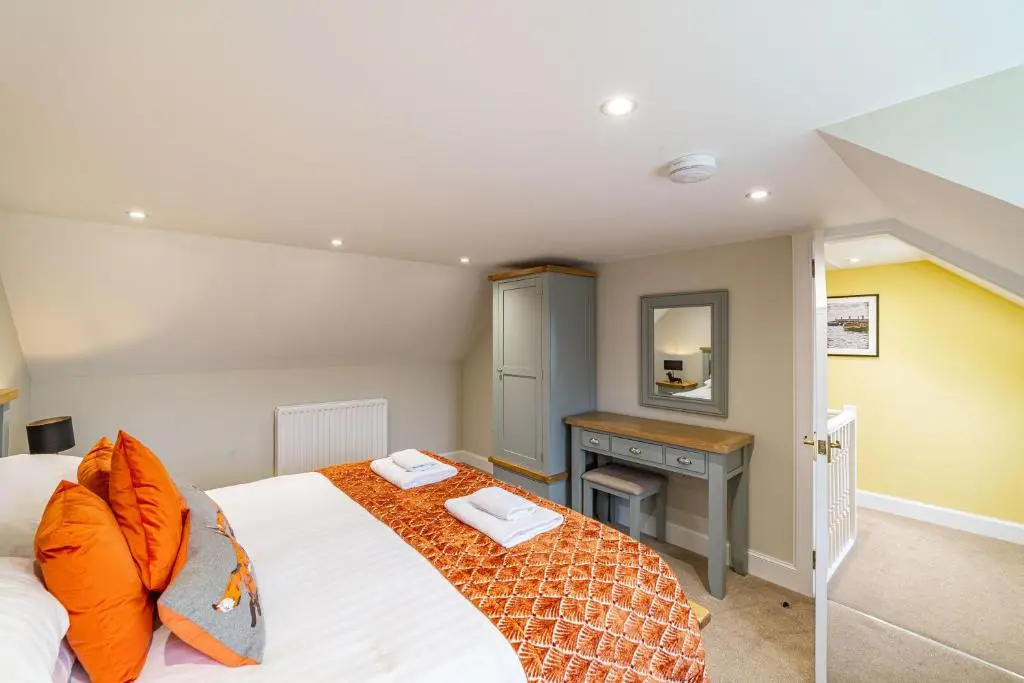 a bedroom with a bed with orange pillows and a desk at Gardener\u2019s Cottage with Hot Tub in Blairgowrie