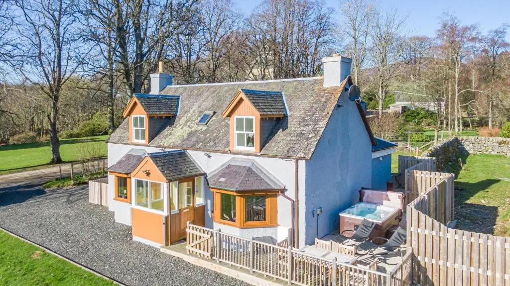a small house with a fence around it at Gardener\u2019s Cottage with Hot Tub in Blairgowrie