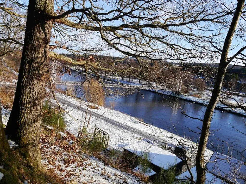 a bridge over a river with snow on the ground at Laundry Cottage in Aberlour