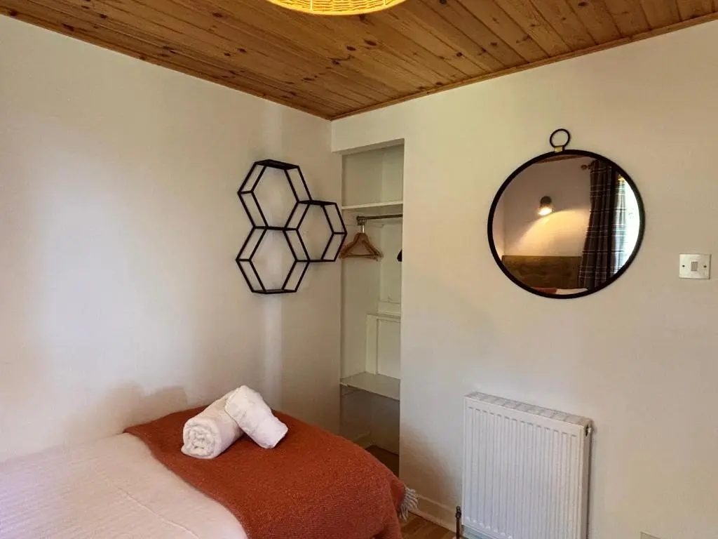 a bedroom with a bed and a mirror on the wall at Bracken Lodge 15 with Hot Tub in Belladrum