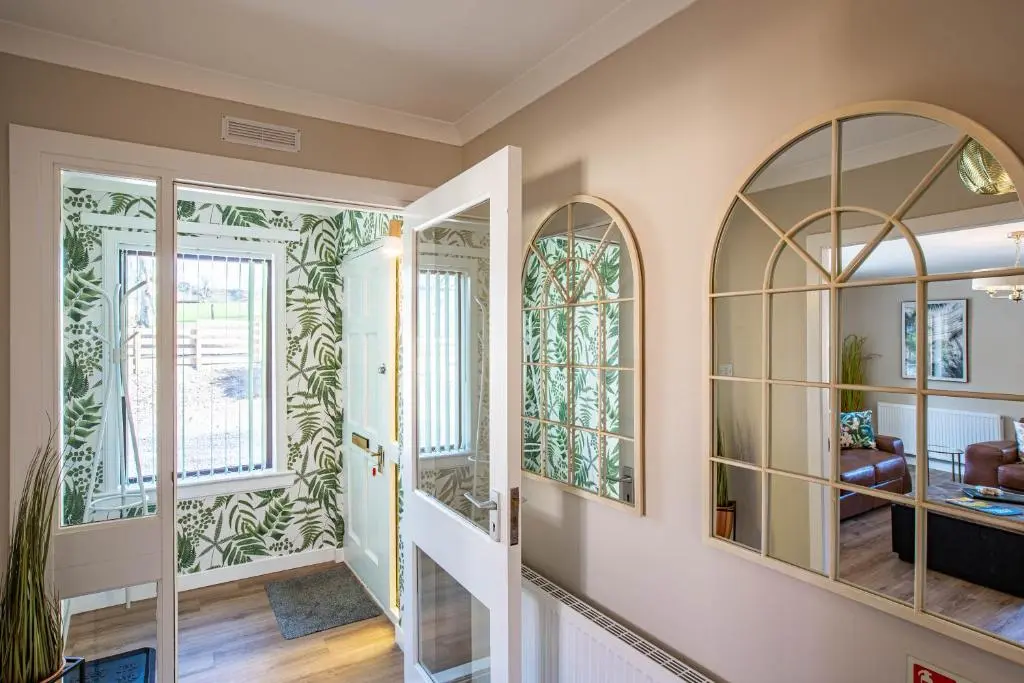 a hallway with arched windows and a staircase with mirrors at Breckland House with Hot Tub in Belladrum