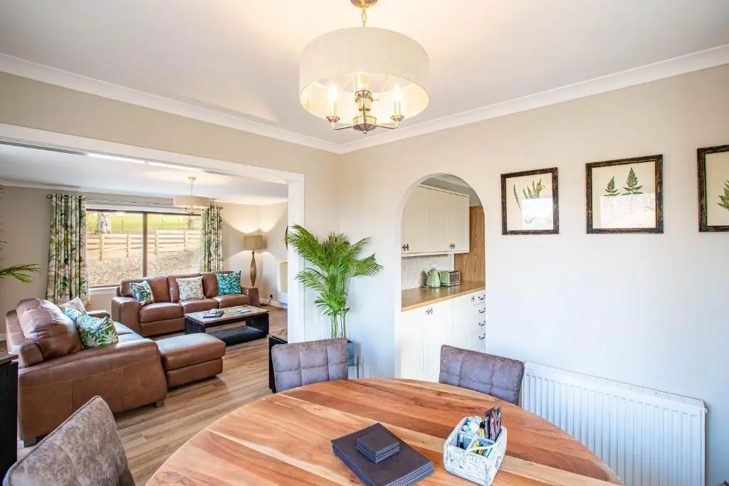a living room with a wooden table and a couch at Breckland House with Hot Tub in Belladrum