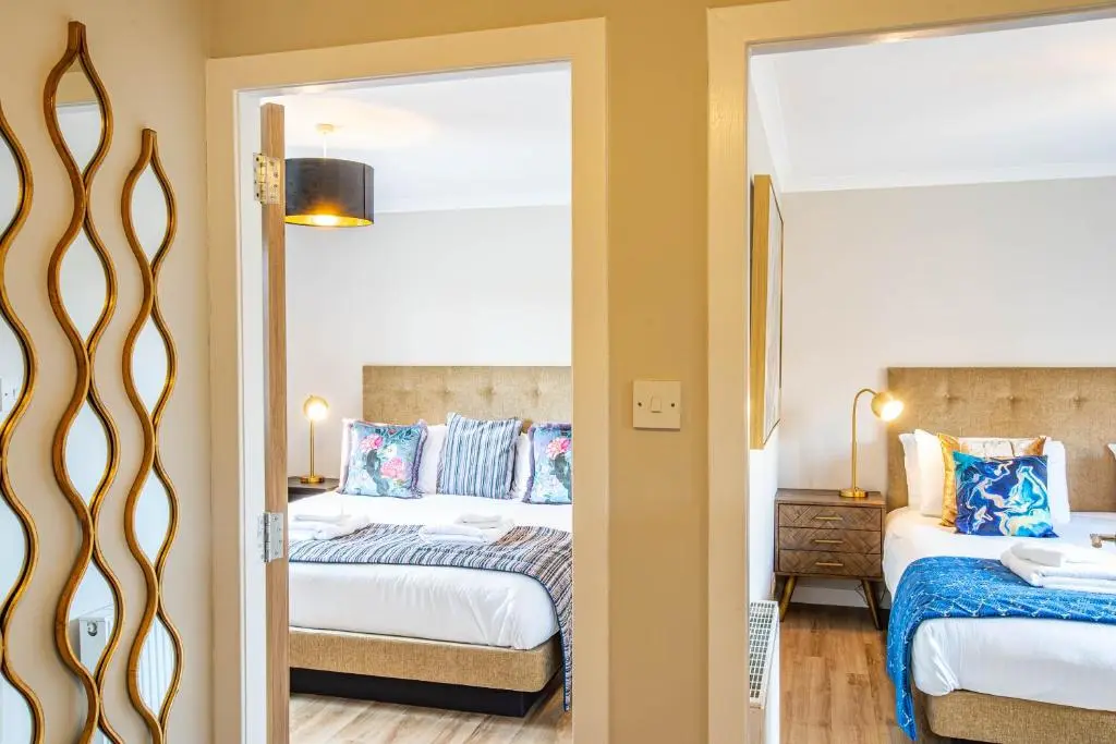 a bedroom with two beds and a mirror at Breckland House with Hot Tub in Belladrum