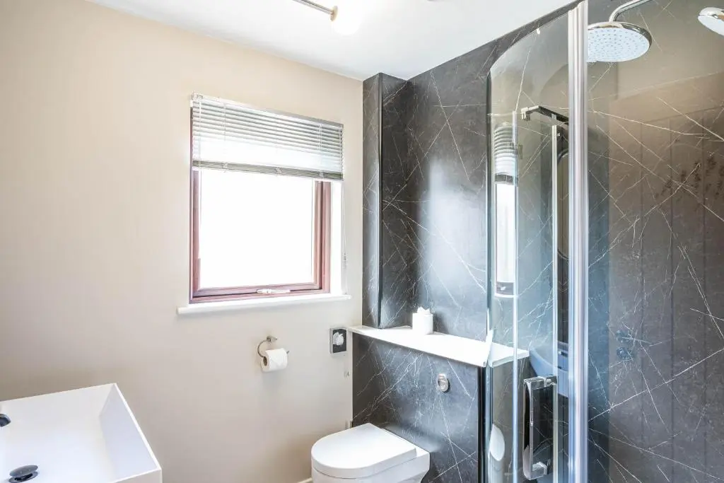 a bathroom with a shower and a toilet and a sink at Breckland House with Hot Tub in Belladrum