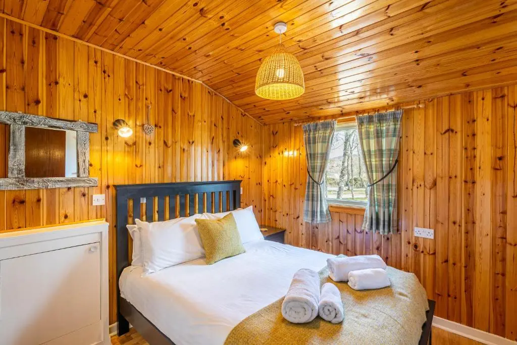a bedroom with a bed and two towels on a table at Heather Lodge 1 with Hot Tub in Belladrum