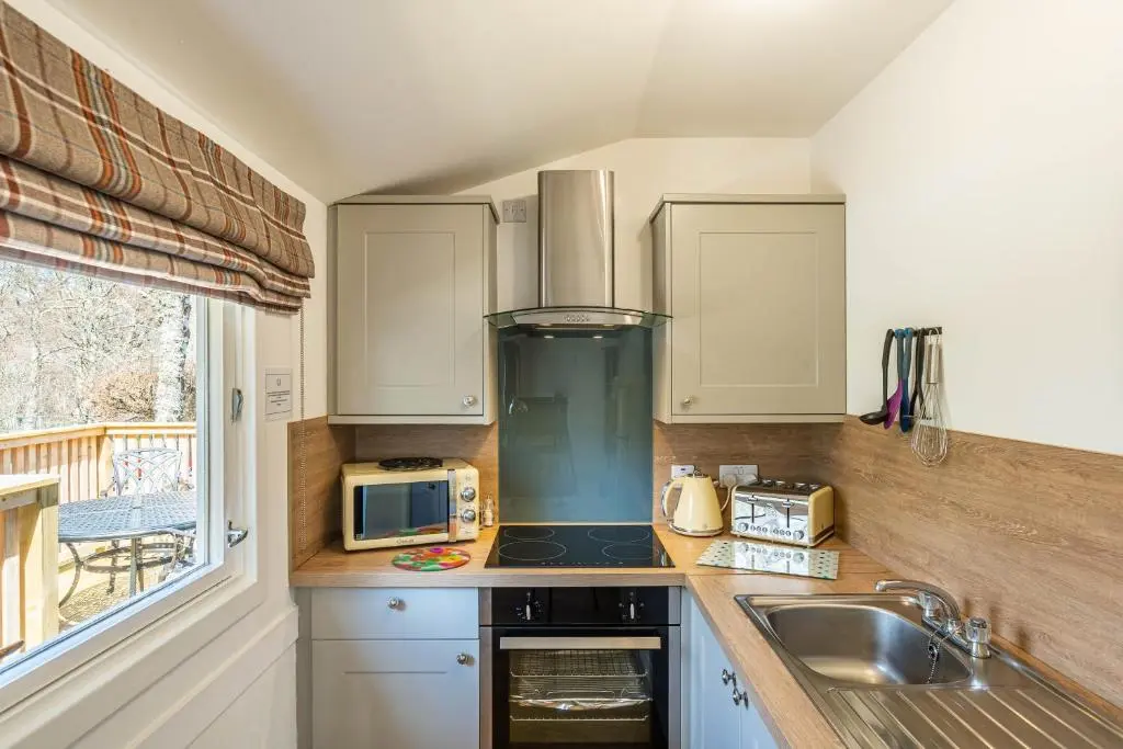 a kitchen with a stove top oven next to a sink at Heather Lodge 1 with Hot Tub in Belladrum