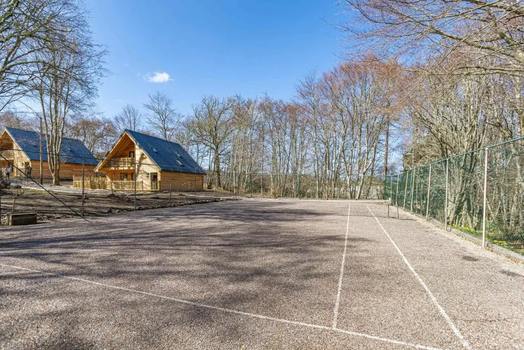 an empty parking lot with a fence and a house at Heather Lodge 1 with Hot Tub in Belladrum