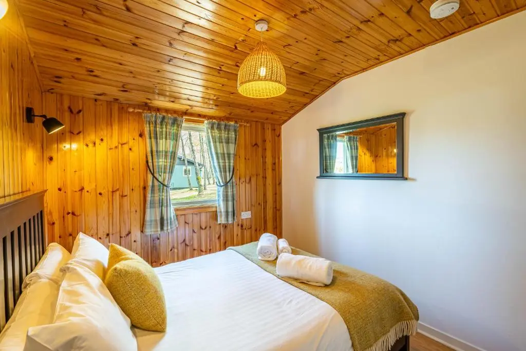 a bedroom with a bed in a room with wooden walls at Heather Lodge 1 with Hot Tub in Belladrum