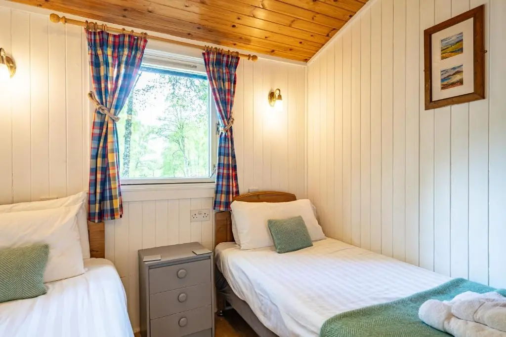 a small bedroom with two beds and a window at Heather Lodge 10 with Hot Tub in Belladrum