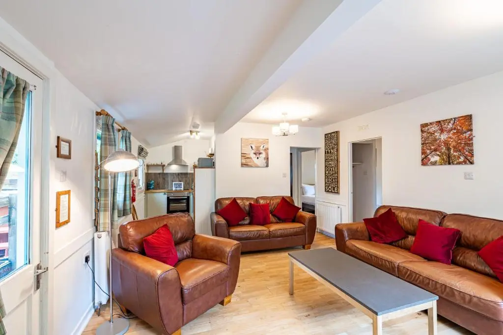 a living room with leather couches and a table at Heather Lodge 10 with Hot Tub in Belladrum