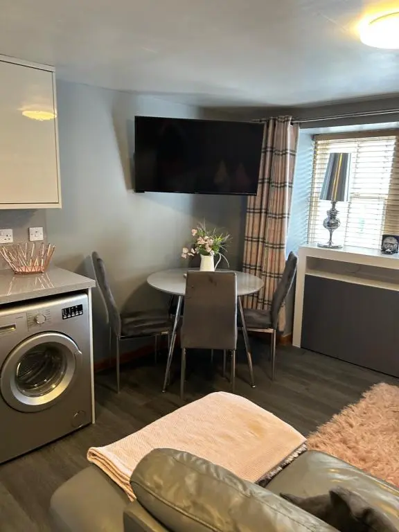 a living room with a table and a kitchen at Saint Blue Apartment in Tain