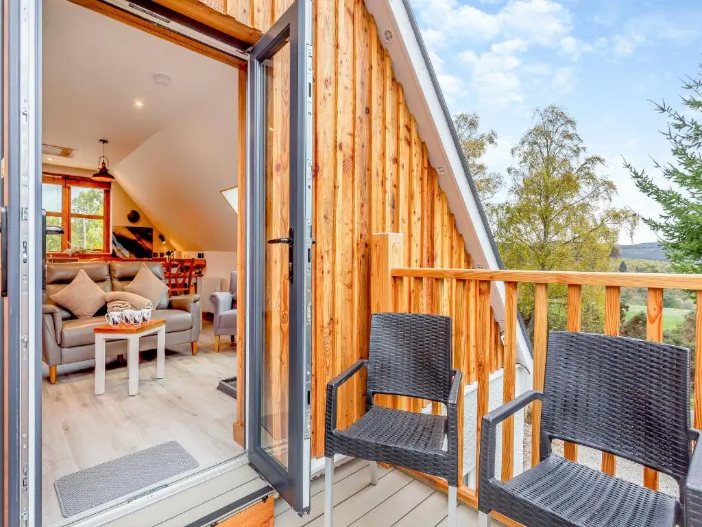 a wooden house with two chairs on a deck at Tigh-Na-Sgoile in Belladrum