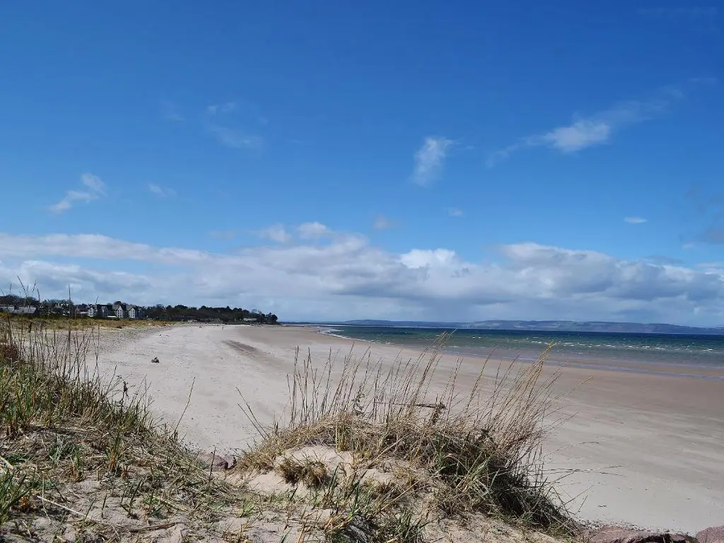 a sandy beach with the ocean in the background at Harbour Apartment in Nairn