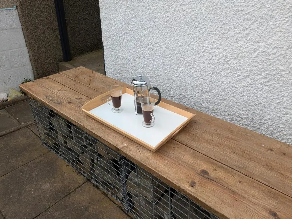 a wooden table with a lantern and two glasses on it at Craigmile Cottage in Fraserburgh