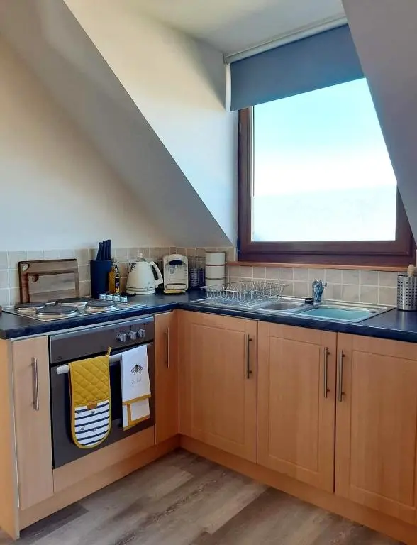 a kitchen with a stove and a sink and a window at Balormie View in Lossiemouth