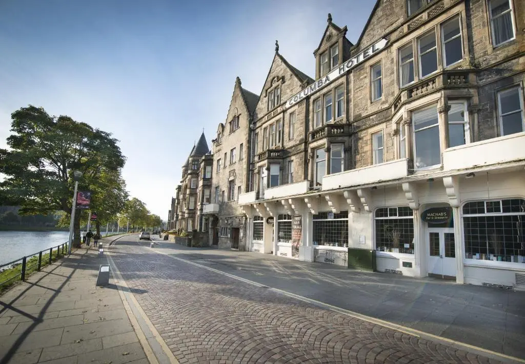 a cobblestone street in front of buildings next to the water at Columba Hotel Inverness by Compass Hospitality in Inverness