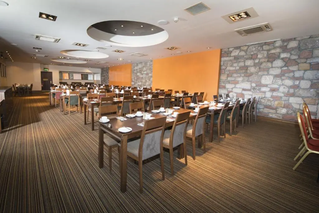 a conference room with tables and chairs and a stone wall at Columba Hotel Inverness by Compass Hospitality in Inverness
