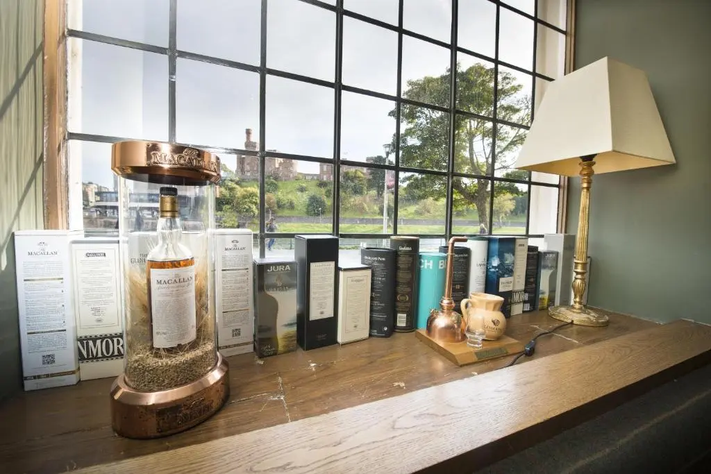 a table with books and a lamp and a window at Columba Hotel Inverness by Compass Hospitality in Inverness