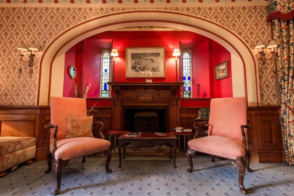 a living room with a fireplace and red walls at Craigmonie Hotel Inverness by Compass Hospitality in Inverness