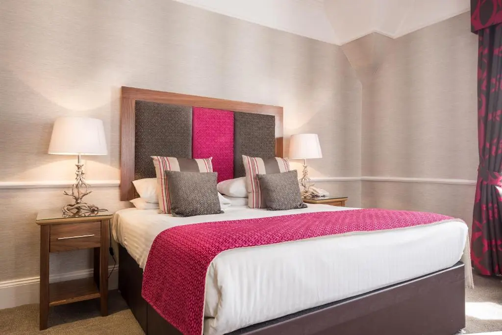 a bedroom with a large bed with a red blanket at Craigmonie Hotel Inverness by Compass Hospitality in Inverness