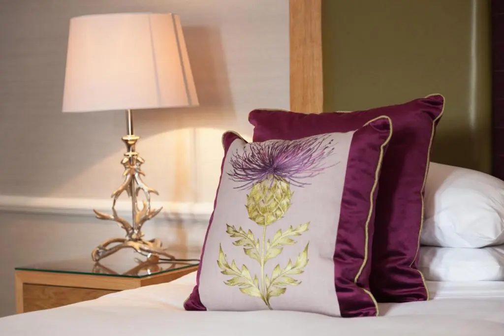 a purple pillow sitting on a bed next to a lamp at Craigmonie Hotel Inverness by Compass Hospitality in Inverness