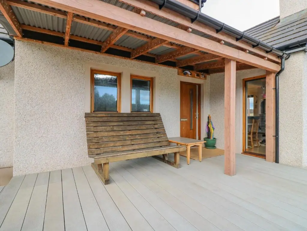 a wooden bench sitting on a porch of a house at Otakaro in Tomintoul