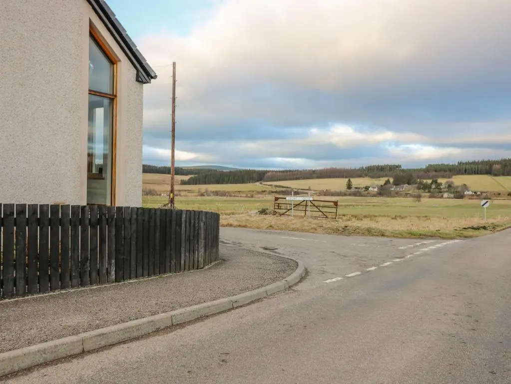 an empty road next to a building with a picnic table at Otakaro in Tomintoul