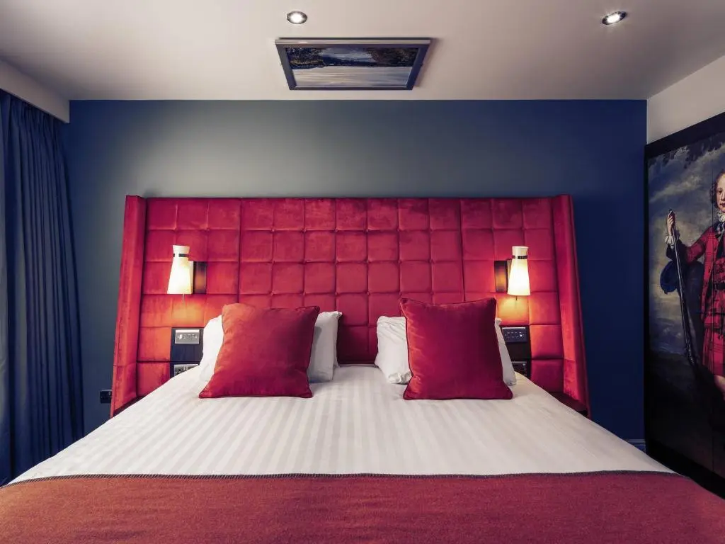a bedroom with a large bed with red headboard at Mercure Inverness Hotel in Inverness