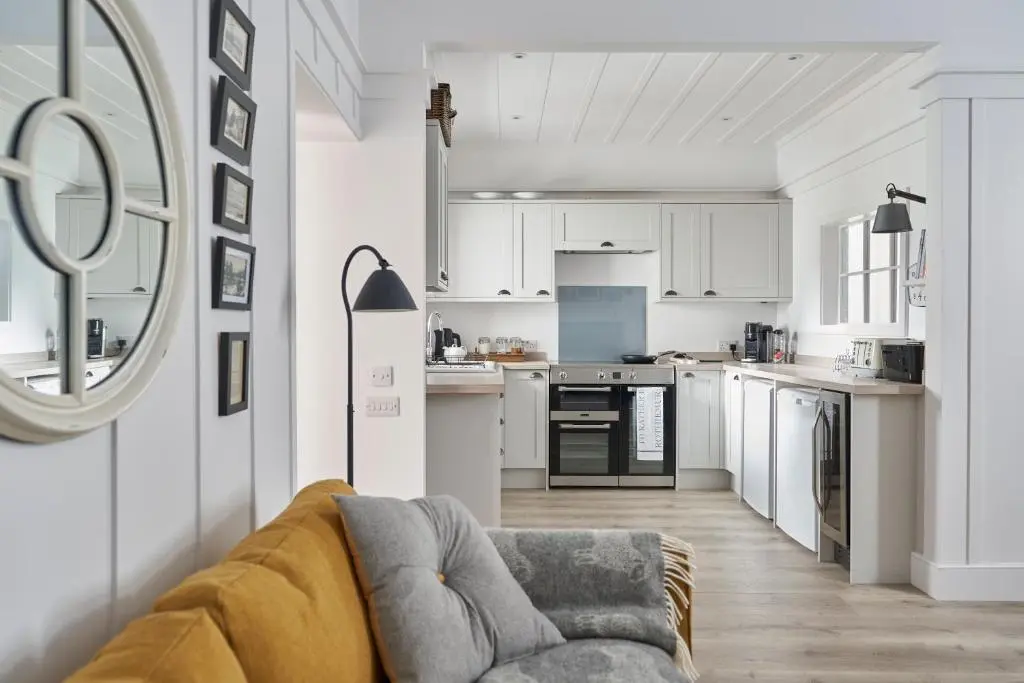 a living room with a couch and a kitchen at Achnahatnich House in Aviemore