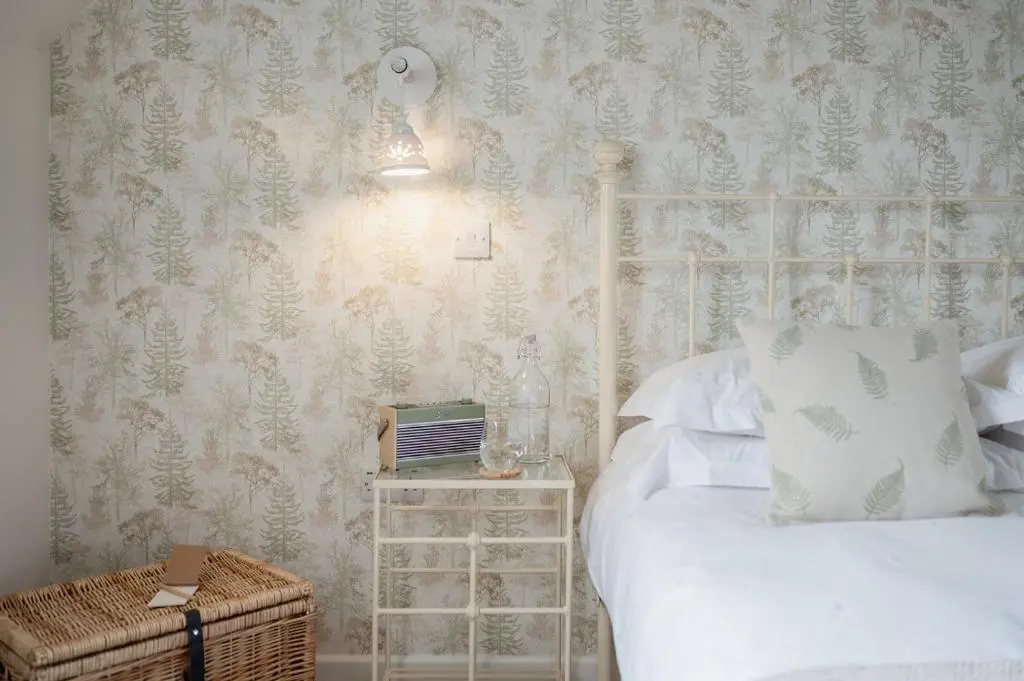 a bedroom with a bed and a night stand next to it at Gleann Cottage - Seasgair Lodges in Kincraig