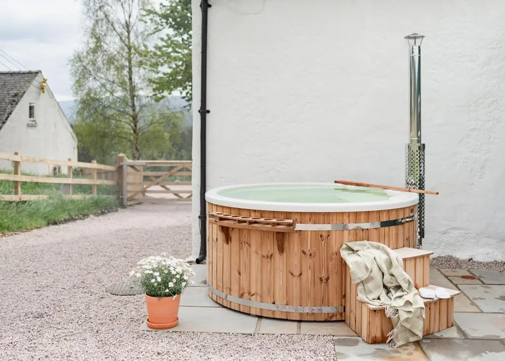 a hot tub sitting outside of a house at Beinn Cottage - Seasgair Lodges in Kincraig