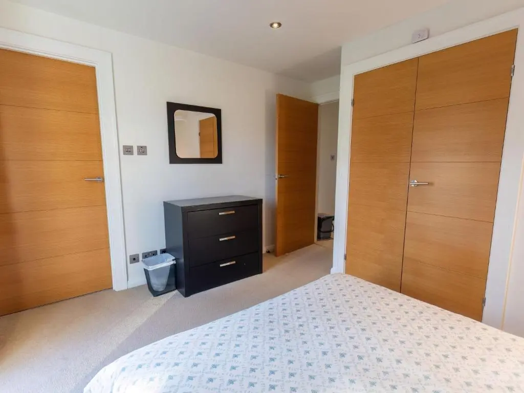 a bedroom with wooden doors and a bed with a dresser at Apartment Druid Temple by Interhome in Inverness