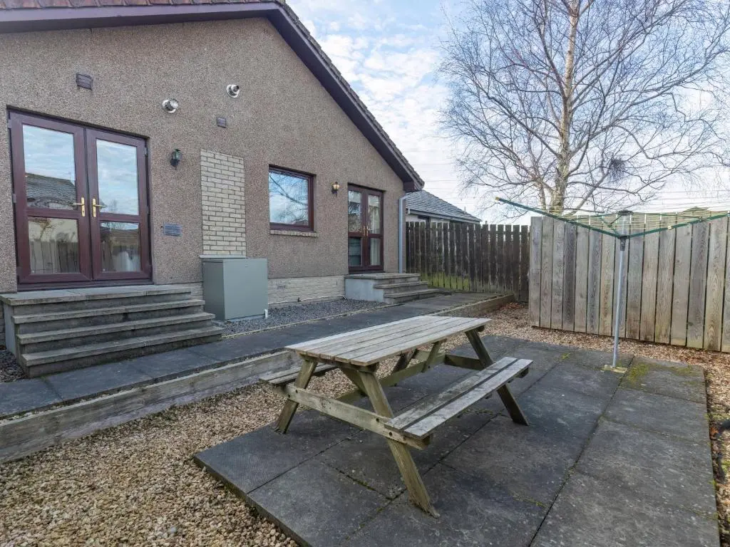 a wooden picnic table in front of a house at Holiday Home Ardness Place by Interhome in Inverness