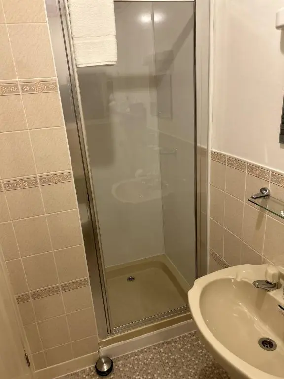 a shower with a glass door next to a sink at Corunna Bed & Breakfast and Corunna Cottage in Inverness