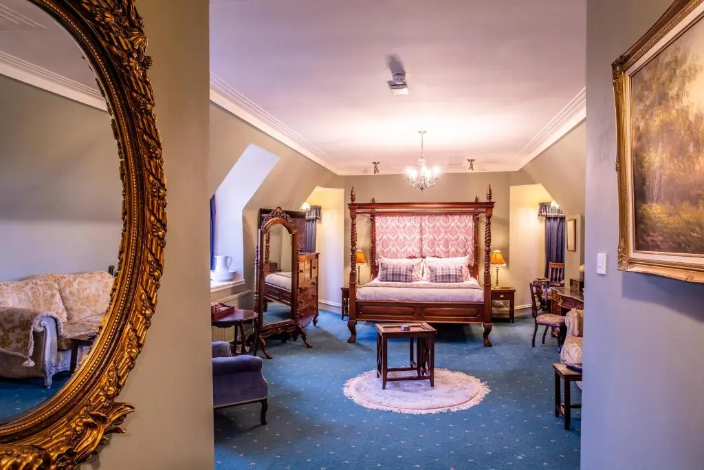 a bedroom with a bed and a mirror at Dalmunzie Castle Hotel in Glenshee
