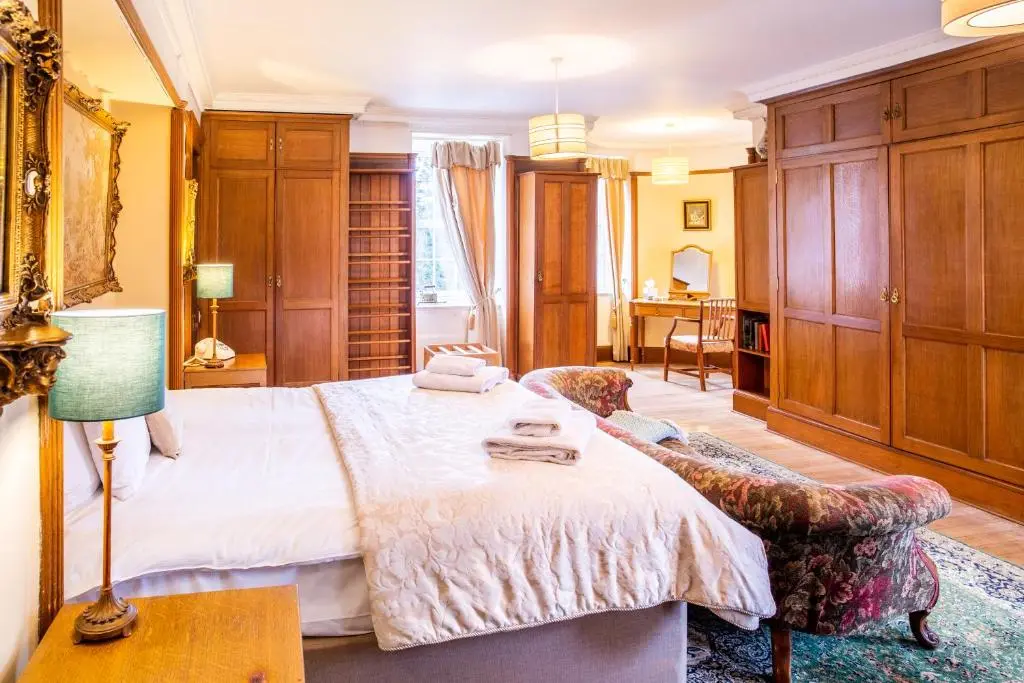 a bedroom with a bed and a lamp and a chair at Dalmunzie Castle Hotel in Glenshee