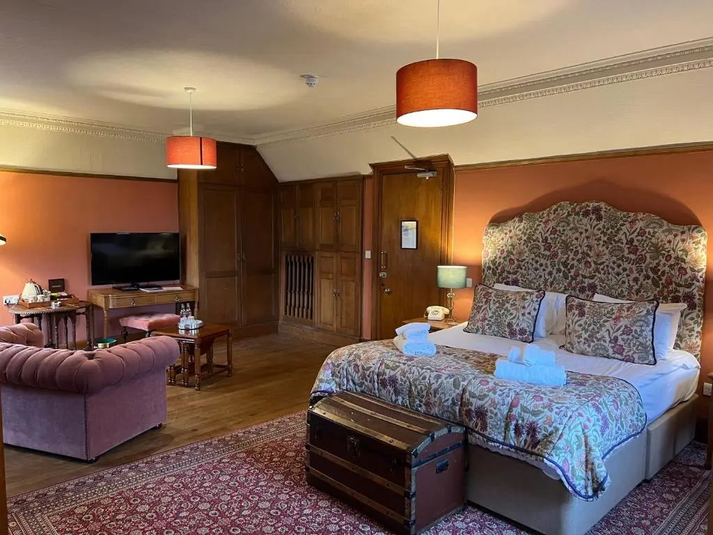 a bedroom with a bed and a living room at Dalmunzie Castle Hotel in Glenshee
