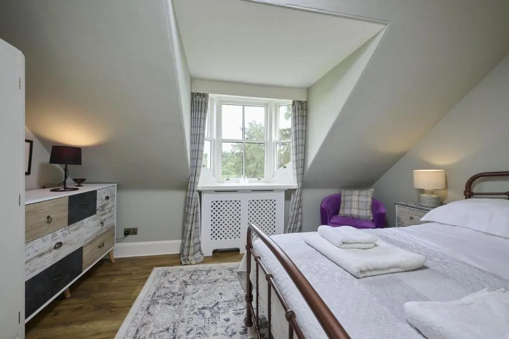 a bedroom with a large bed and a window at Dunaincroy Farmhouse in Inverness