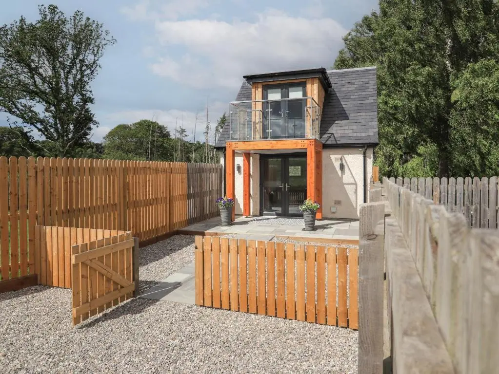 a house with a wooden fence in a yard at Wee Smithy in Munlochy