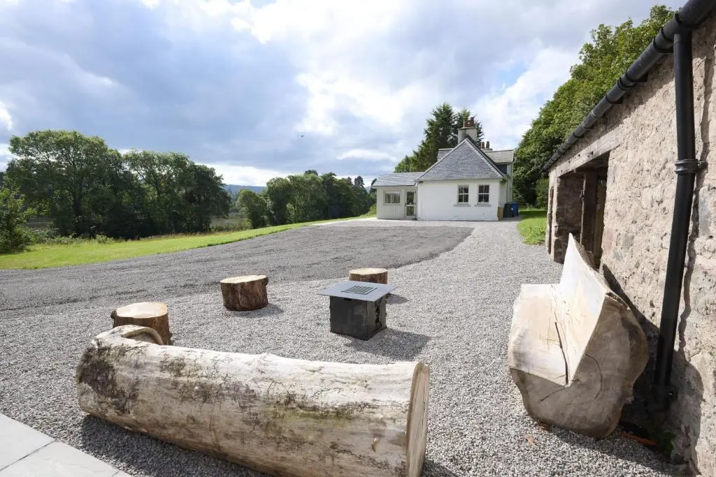a building with a large log next to a road at Middleton Farmhouse in Inverness